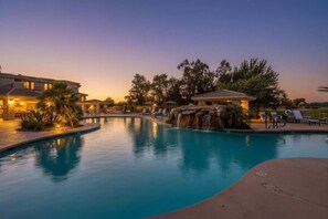 A swimming pool with a waterfall feature, lounge chairs, and a building with a patio. - Scottsdale Pad Steps to Kierland | Pool | Spa (Scottsdale)
