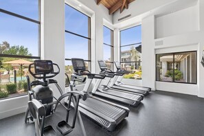 A gym with treadmills, ellipticals, and a stationary bike, large windows, and a view of a pool and buildings. - Scottsdale Pad Steps to Kierland | Pool | Spa (Scottsdale)