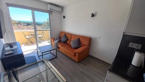 A modern living space with a sofa, a glass table, and a view of the outdoors. - Modern Duplex in Cabopino Beach, with swimming pool and parking. (Marbella)