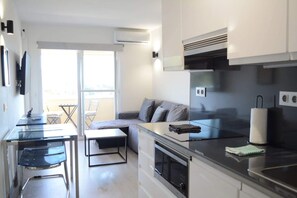 A modern kitchen with a dining area, a sofa, and a TV. - Modern Duplex in Cabopino Beach, with swimming pool and parking. (Marbella)