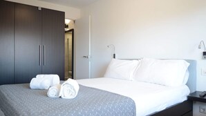Une chambre d’hôtel comprenant un lit, une armoire, une table de chevet et une petite table.