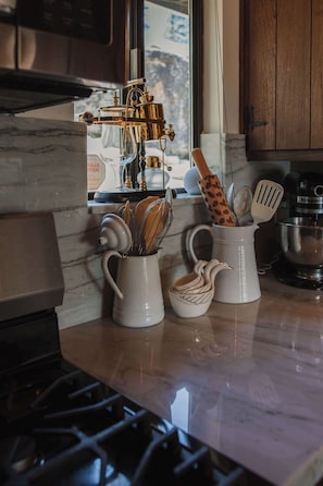 Una cocina equipada con estufa, cafetera y diferentes utensilios.