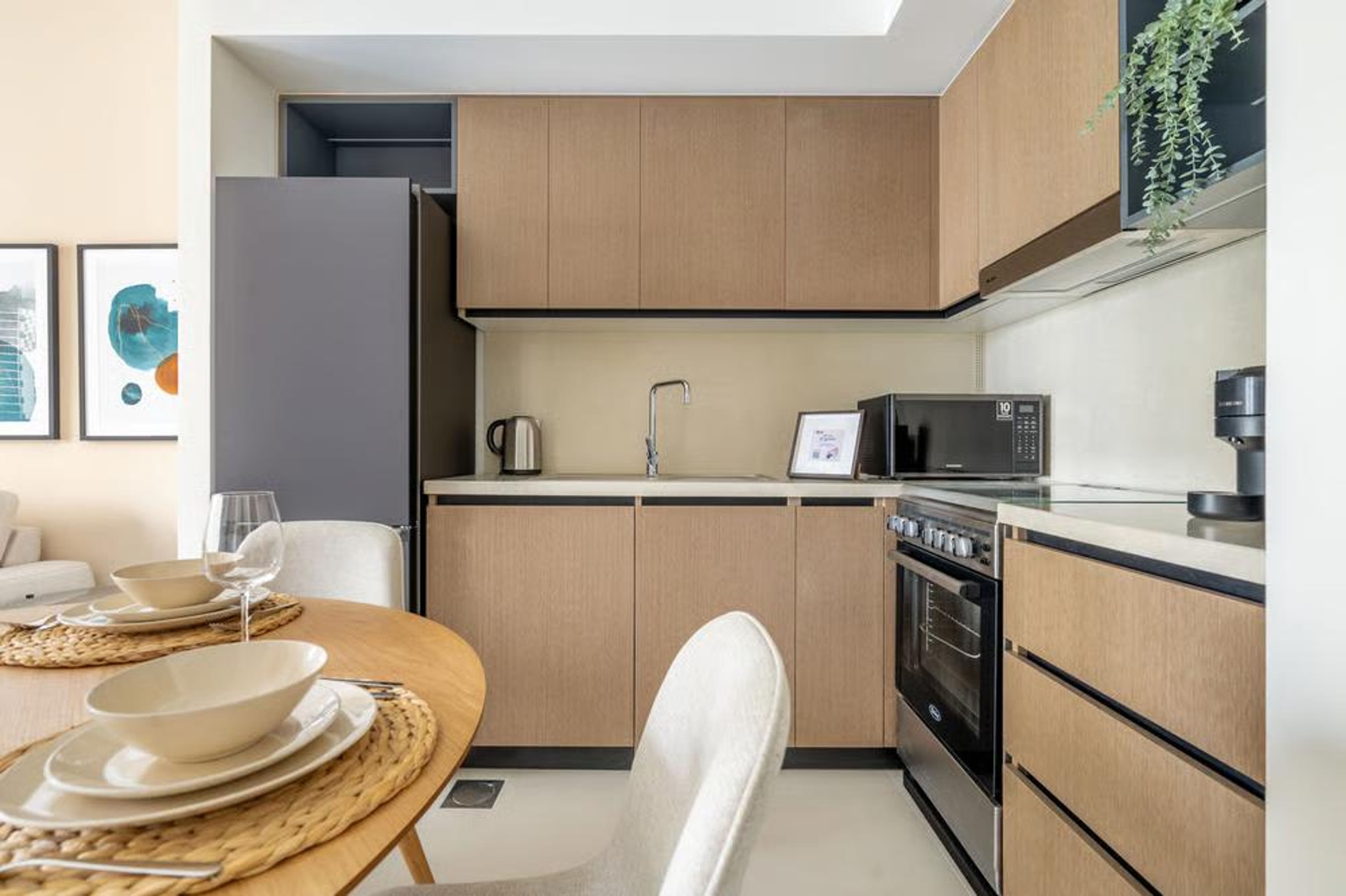A modern kitchen with wooden cabinets, a microwave, an oven, and a dining area with a table and chairs.