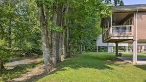 A house with a covered porch, a lawn, and a stream. - Welcome to Ritz on the River, your peaceful Smoky Mountain retreat! (Pigeon Forge)