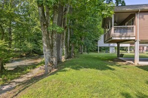 A house with a covered porch, a lawn, and a stream. - Welcome to Ritz on the River, your peaceful Smoky Mountain retreat! (Pigeon Forge)