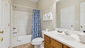 A bathroom with a bathtub, toilet, sink, and shower curtain. - Welcome to Ritz on the River, your peaceful Smoky Mountain retreat! (Pigeon Forge)