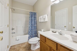 A bathroom with a bathtub, toilet, sink, and shower curtain. - Welcome to Ritz on the River, your peaceful Smoky Mountain retreat! (Pigeon Forge)