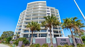 Ein mehrstöckiges Hotel mit Balkonen, Palmen und einem Schild mit der Aufschrift 'THE COVE'.