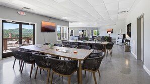 A conference room with a large table, chairs, a TV, and a view of the outdoors. - Serenity Ridge Clubhouse - 6 Units/Big Groups/Pool (Pigeon Forge)