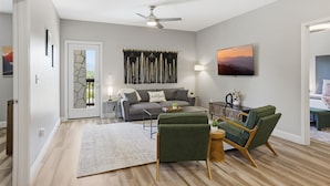 Un salon comprenant un canapé, des fauteuils, une table basse, un téléviseur et un ventilateur de plafond.