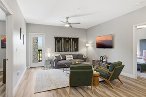Un salon comprenant un canapé, des fauteuils, une table basse, un téléviseur et un ventilateur de plafond.