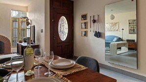 A dining area with a wooden table set for four, a wine bottle, and wine glasses. - Quiet and Cozy Home with Great Location (Queretaro)