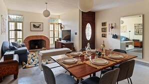 A dining area with a wooden table set for four, a fireplace, and a television in the background. - Quiet and Cozy Home with Great Location (Queretaro)