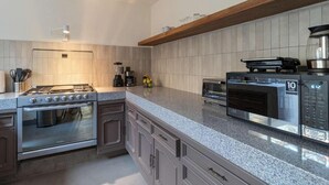 A modern kitchen with a granite countertop, stainless steel appliances, and a built-in oven. - Quiet and Cozy Home with Great Location (Queretaro)