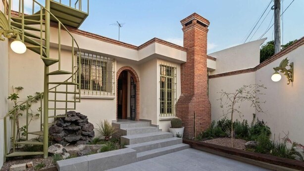 A house with a spiral staircase, a brick chimney, and a stone wall. - Quiet and Cozy Home with Great Location (Queretaro)