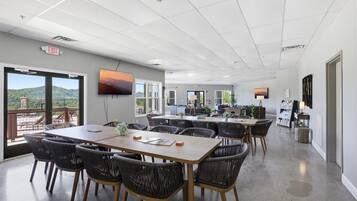 A conference room with a large table, chairs, a TV, and a view of the outdoors.