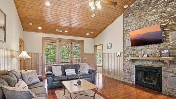 A living room with a stone fireplace, a flat-screen TV, and a wooden ceiling. - Serenity Ridge 322 - Pool Table/Patio/Pool Access (Pigeon Forge)