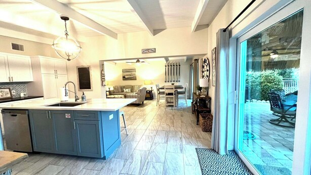 Een moderne keuken met een centraal eiland, een eethoek met een tafel en stoelen, en een grote schuifpui naar een terras.