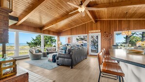 Uma sala de estar ampla com um sofá grande, um balcão de refeições e vista para o oceano.