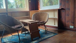 A room with two wicker chairs, a small wooden table, and a blue patterned rug.
