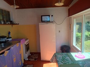A compact kitchen with a microwave, refrigerator, stove, and sink.