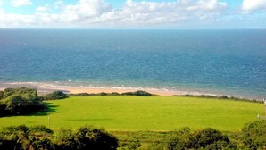 Un paisaje costero con un campo cubierto de hierba, una playa y el océano.