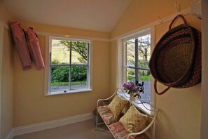 A room with a bench, two windows, and a basket on the wall.