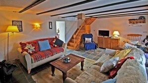 Ein gemütliches Wohnzimmer mit einer Couch, einem Sessel und einer Holztreppe.