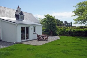 A white house with a patio, a table, and chairs.