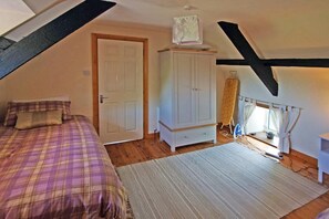 A bedroom with a bed, a wardrobe, a radiator, and a window with curtains.