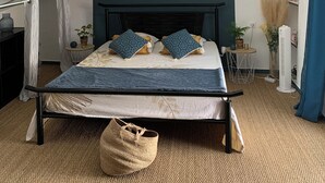 A bedroom with a sloped ceiling, a bed with patterned bedding, a bedside table with a lamp, and a small side table with a vase. - The daring home between sea and mountains perfect for family vacations (Cazouls-lès-Béziers)