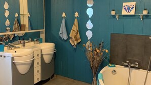 A bathroom with a white sink, two mirrors, a bathtub, and a blue wall. - The daring home between sea and mountains perfect for family vacations (Cazouls-lès-Béziers)