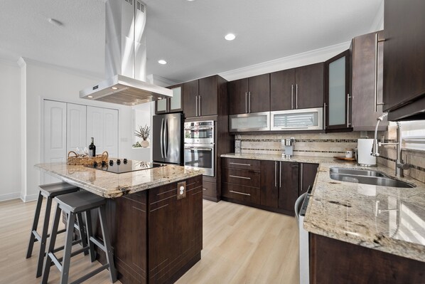 A modern kitchen with dark wood cabinets, stainless steel appliances, and a granite countertop.