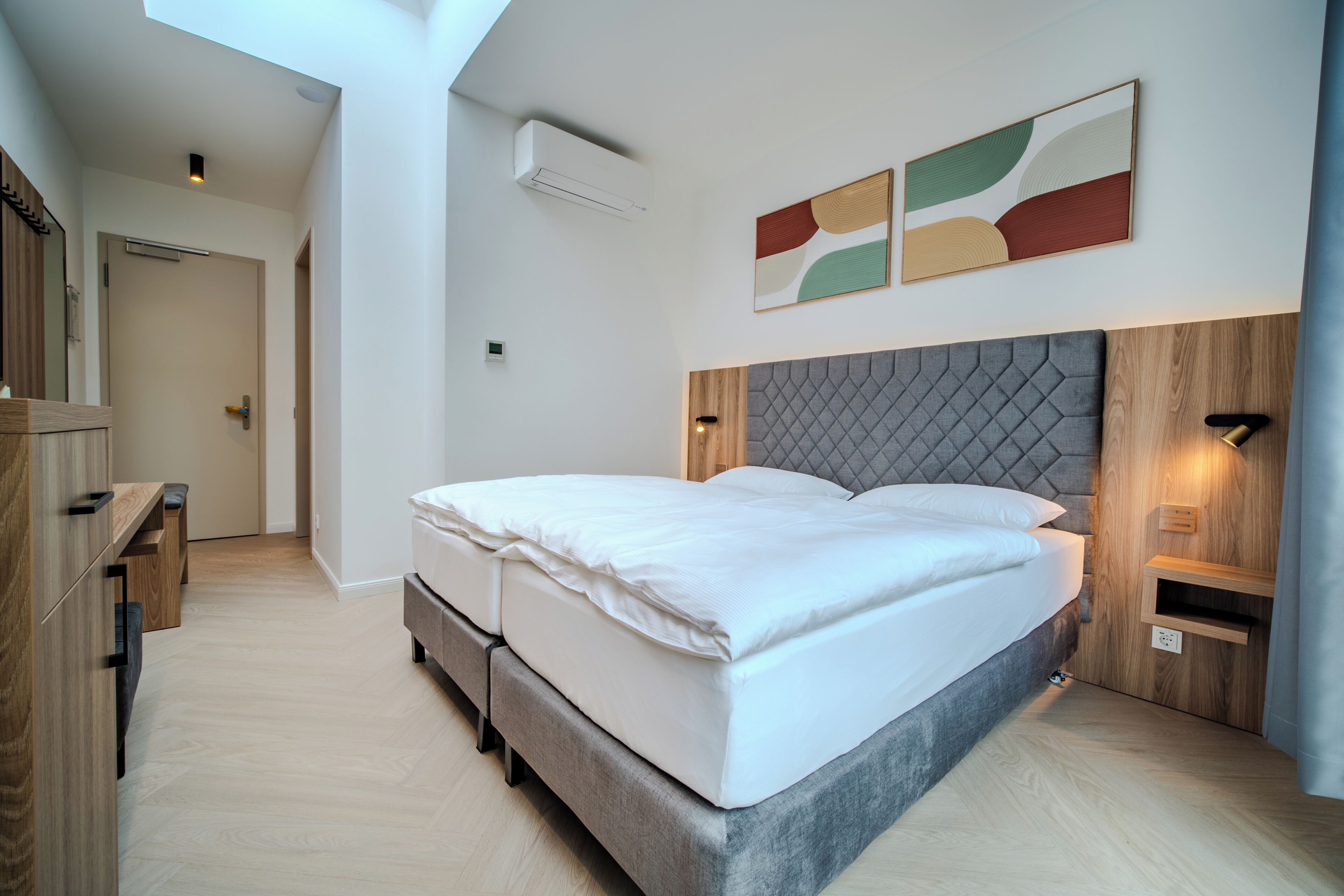 Un dormitorio moderno con cama, muebles de madera y una lámpara de techo.