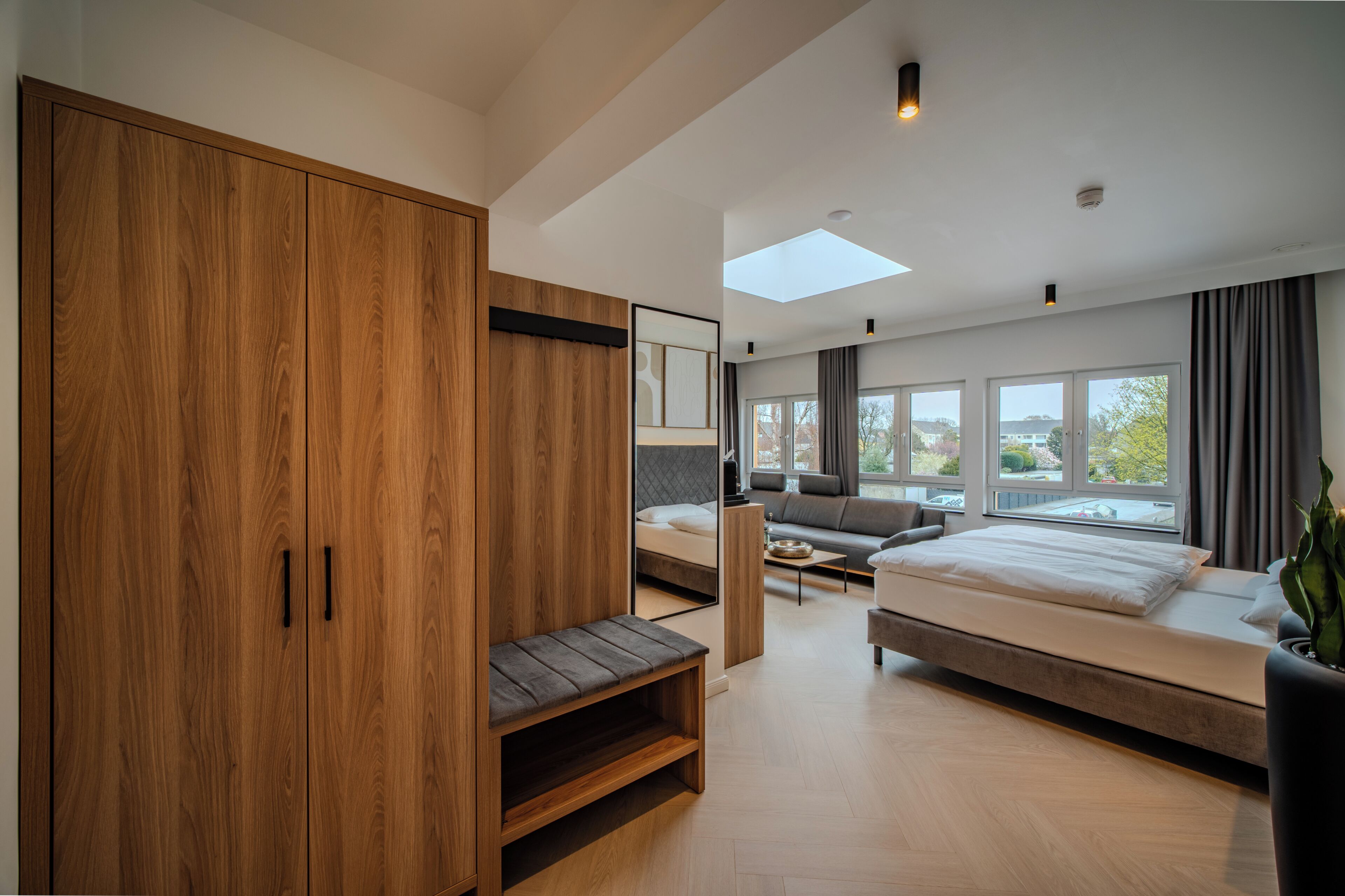 A modern bedroom with a large wardrobe, a bed, a sofa, and a skylight.