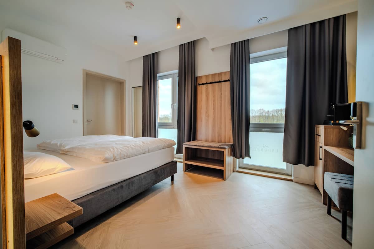 Un dormitorio moderno con cama, mesita de noche y vistas al exterior.