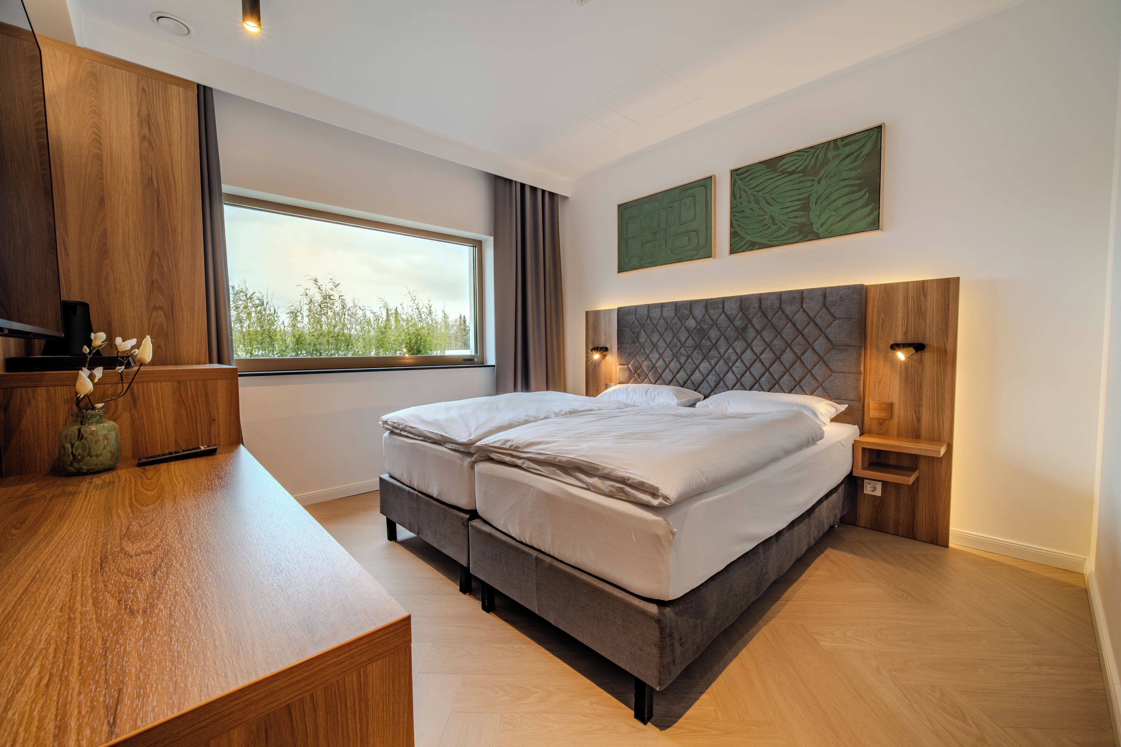 Un dormitorio moderno con una cama grande, un escritorio y una ventana con vistas.