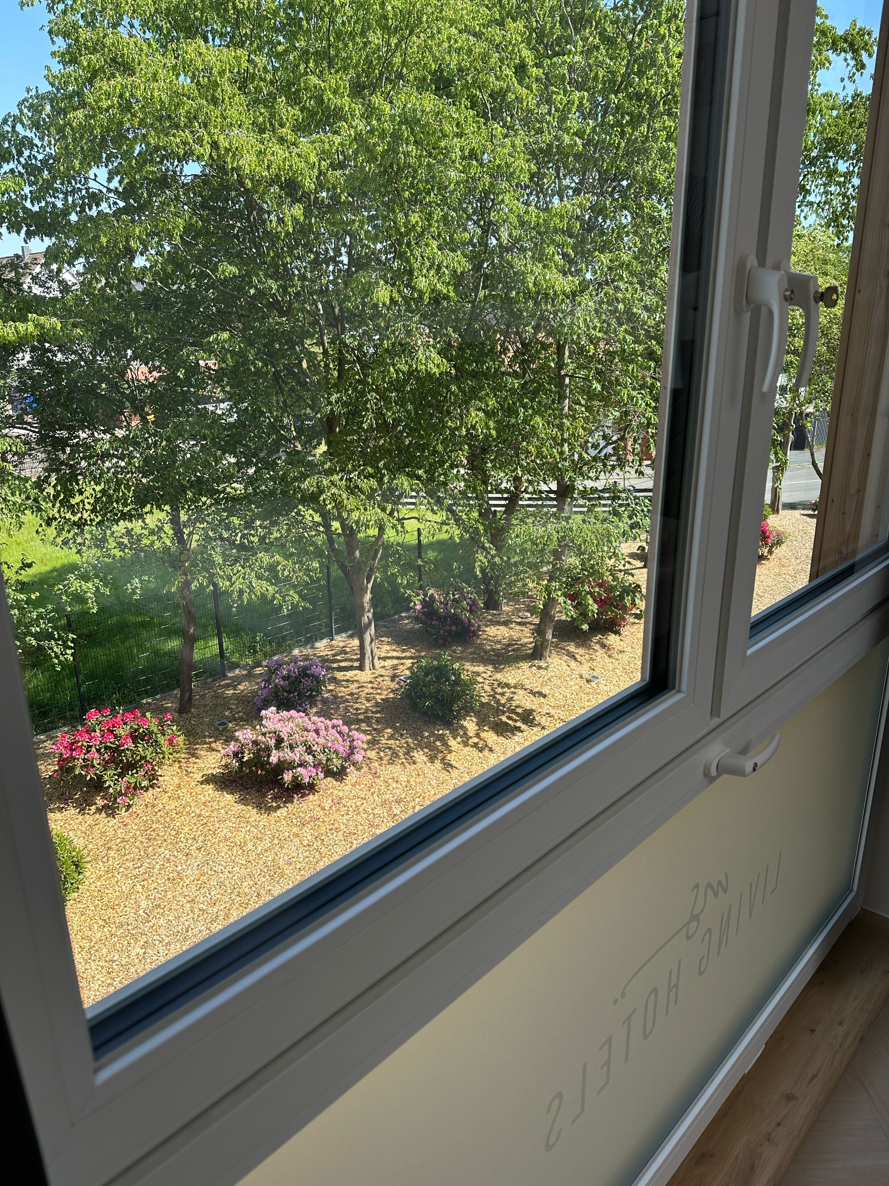 A room with a large window, a wooden floor, and a door with a handle.