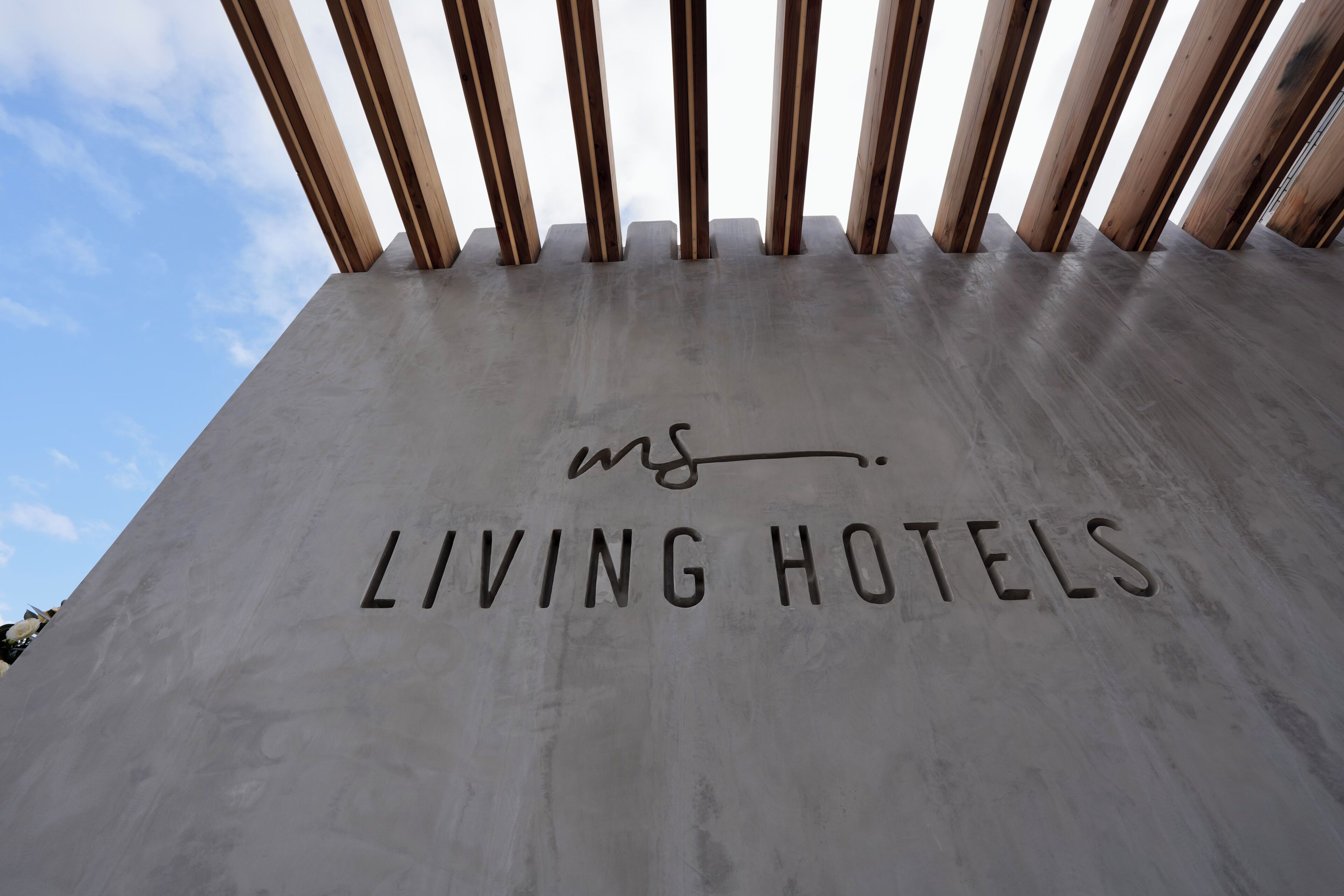 A concrete wall with the text 'LIVING HOTELS' and a partial view of wooden beams.