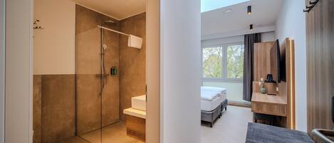 A modern bathroom with a glass shower enclosure, a wooden bench, and a large mirror.