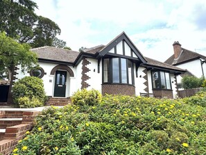 A two-story house with a prominent bay window, a front door with a circular window, and a brick chimney. - 3-BR Bungalow w/ Spacious Living & Private Garden (Lincolnshire)