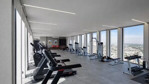 Ein Fitnessstudio mit Laufbändern, Kraftgeräten und Blick auf die Stadt.