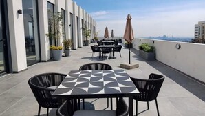 Eine Dachterrasse mit Sitzgelegenheiten im Freien, Kübelpflanzen und Blick auf die Stadtlandschaft.