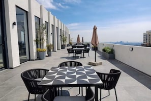 Eine Dachterrasse mit Sitzgelegenheiten im Freien, Kübelpflanzen und Blick auf die Stadtlandschaft.