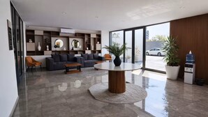 Eine moderne Lobby mit einem runden Tisch, Sofas und einem großen Fenster mit Blick auf ein Auto.