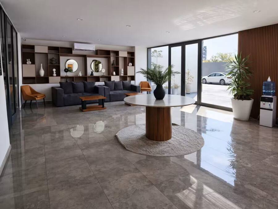 Eine moderne Lobby mit einem runden Tisch, Sofas und einem großen Fenster mit Blick auf ein Auto.
