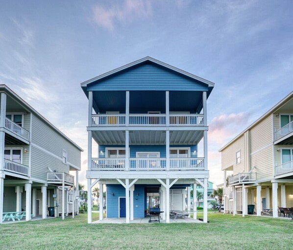 Un motel à deux étages doté d’un balcon central, d’une véranda couverte et d’un petit espace extérieur aménagé pour s’asseoir.