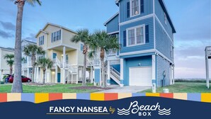 A beachfront property with multiple-story buildings, a visible garage, and a staircase leading to the upper floors.