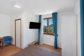 A bedroom with a bed, a TV, a window with curtains, a chair, and a small table. - 'Elea' Room with Sea View, Wi-Fi and Air Conditioning (Serramezzana)