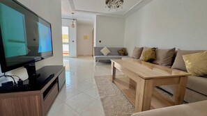 Un salon avec un téléviseur, un canapé et une table basse.